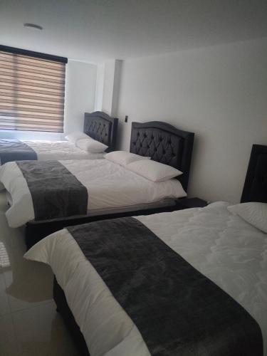 1 dormitorio con 3 camas en una habitación en Hotel Cacique, en Duitama
