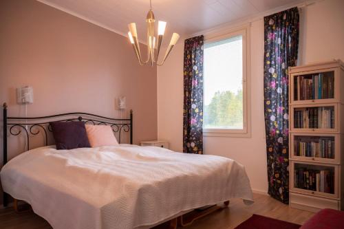 een slaapkamer met een bed, een raam en een kroonluchter bij Villa Puistola & sauna, near Santa's Village in Rovaniemi