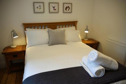 1 dormitorio con 1 cama con toallas y 2 lámparas en The Gardeners Cottage, en Pitlochry