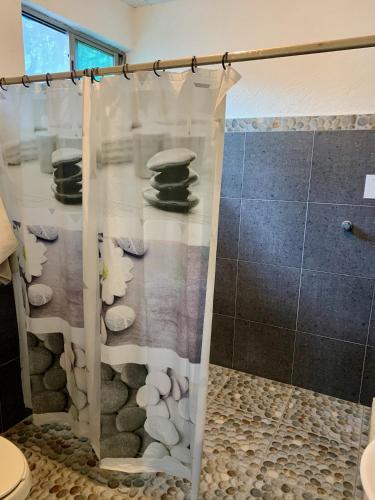a bathroom with a shower curtain with rocks at Casa Borush by Ecoplaneta in Cancún