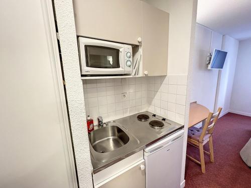 a small kitchen with a sink and a microwave at ValHôtel - Hôtel-Résidence Châteaufort in Châteaufort
