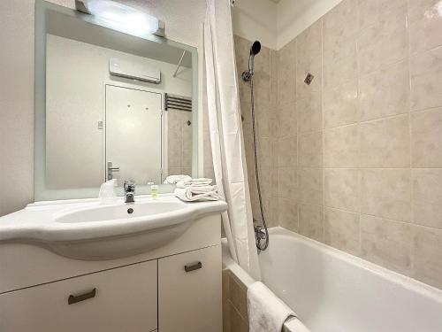 La salle de bains est pourvue d'un lavabo, d'une baignoire et d'un miroir. dans l'établissement ValHôtel - Hôtel-Résidence Châteaufort, à Châteaufort