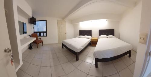 Cette chambre comprend 2 lits et un lavabo. dans l'établissement Hotel el Cortes, à Aguascalientes