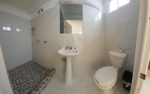 een witte badkamer met een toilet en een wastafel bij Hotel el Cortes in Aguascalientes