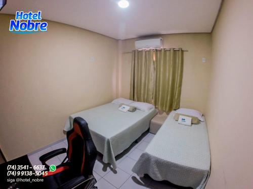 a hospital room with two beds and a chair at Hotel Nobre in Senhor do Bonfim