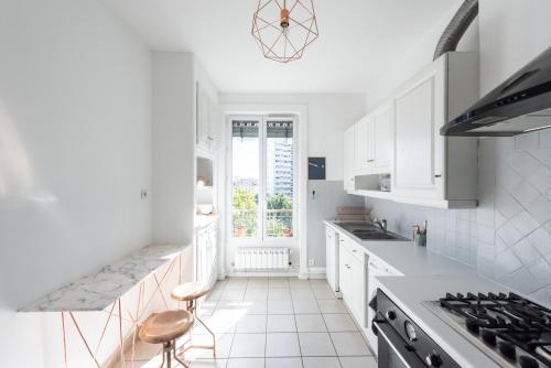 une cuisine avec des armoires blanches et une cuisinière dans l'établissement Le Dandy - Grand T3 au pied du métro Garibaldi, à Lyon