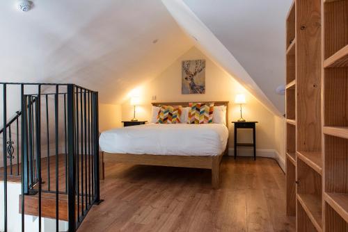 a bedroom with a bed with two lamps and a staircase at Kylemore House boutique apartments - Connemara Suite in Kylemore
