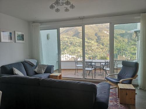 a living room with a couch and chairs and a balcony at Guejar Sierra House with Spectacular Views in Güéjar-Sierra