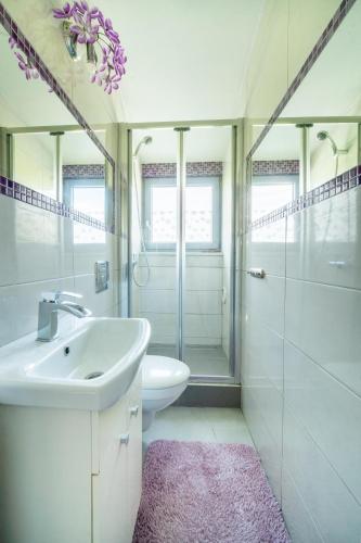 a white bathroom with a sink and a toilet at Całoroczny dom na Mazurach WrzoSPA z jacuzzi in Stare Juchy