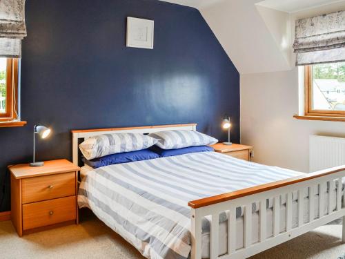 um quarto com uma cama com uma parede azul em Bramble Cottage em Dalry