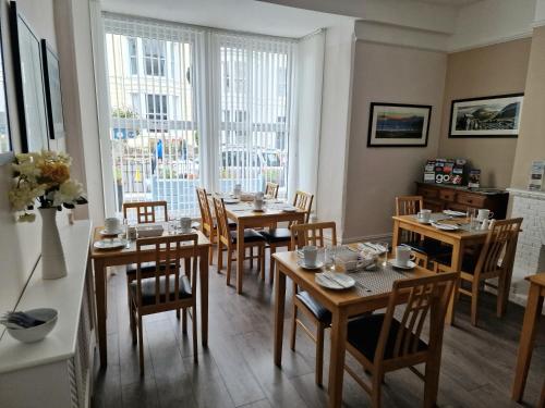 uma sala de jantar com mesas e cadeiras e uma janela em Breeze B&B em Llandudno