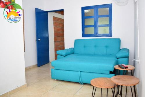 a living room with a blue couch and two stools at HOSTAL LA MACARENA in El Zaino