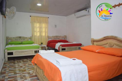a bedroom with two beds with orange and white sheets at HOSTAL LA MACARENA in El Zaino