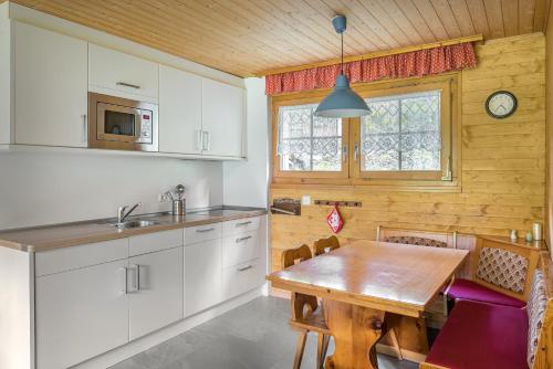 ベットマーアルプにあるJadwiga EGの白いキャビネットと木製テーブル付きのキッチン