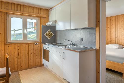 a kitchen with white cabinets and a sink and a window at Lotus UG in Fiesch