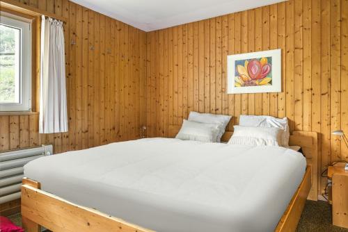 a bedroom with a large bed in a wooden wall at Lotus UG in Fiesch