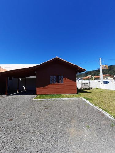 a red building with a roof on a gravel road at Pousada Morada dos Sonhos in Urubici