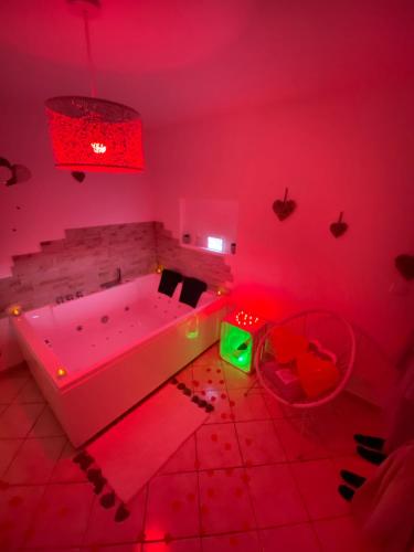 un bagno con vasca e luci rosse di La pomme d’amour a Saint-Genest-Lerpt