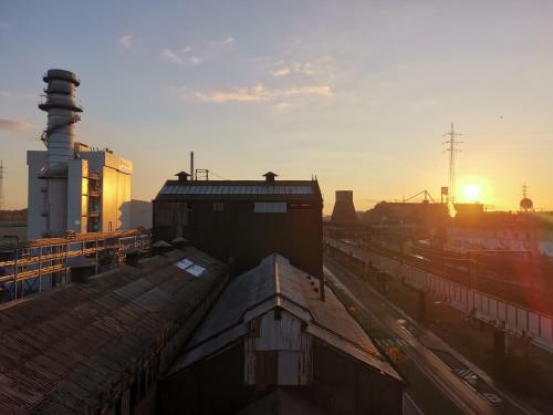a view of a train station with the sun setting at Adventure Alternative - GUEST HOUSE - Arts-Factory-Experience - For artists, makers and open minds - Attention, we are not a hotel and are not adapted for everybody - Read host warnings before reservation - PROVIDENCE,BE asbl in Charleroi