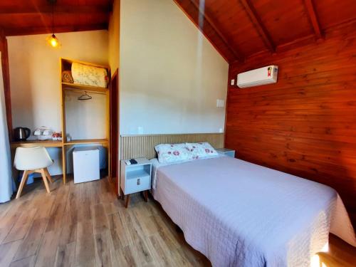 a bedroom with a bed and a desk and a chair at Pousada Morada dos Sonhos in Urubici