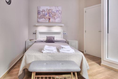 a small bedroom with a bed and a stool at Apartamentos Menorá in Toledo