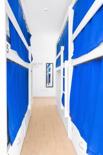 a hallway with blue and white garage stalls at Ínsua Hostel in São Pedro do Sul