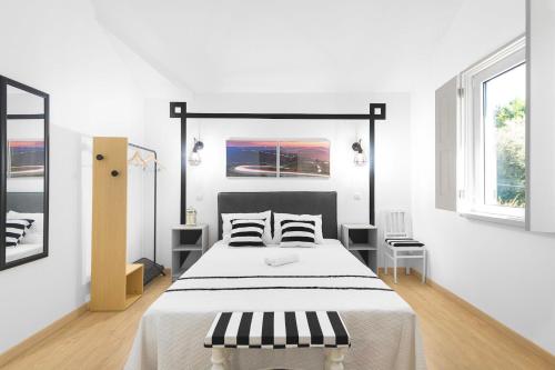 a white bedroom with a large bed and two windows at Ínsua Hostel in São Pedro do Sul