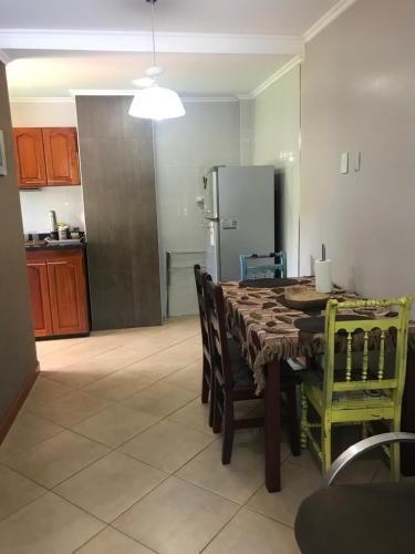 a kitchen with a table with chairs and a refrigerator at Ocio Apart in Puerto Iguazú