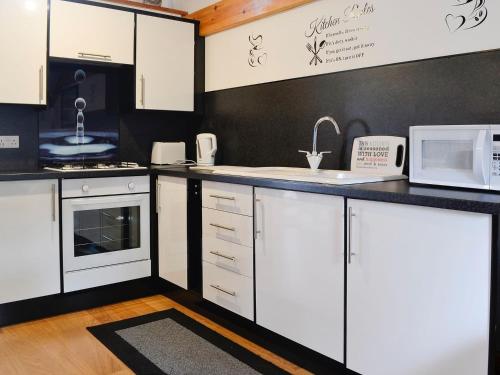 a kitchen with white cabinets and a black wall at Swallow Cottage - Ukc3427 in Dalston