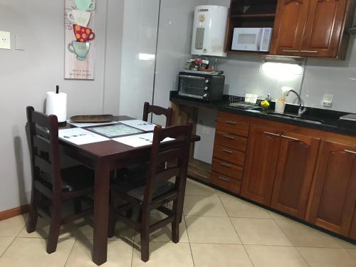 a kitchen with a table and chairs and a microwave at Ocio Apart in Puerto Iguazú