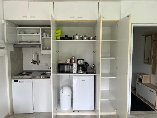 a small kitchen with white cabinets and shelves at Ruhiges und klimatisiertes Apartment in Stuttgart