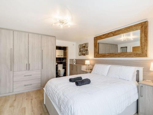 1 dormitorio con 1 cama blanca grande y espejo en The Paddocks, en Ault Hucknall