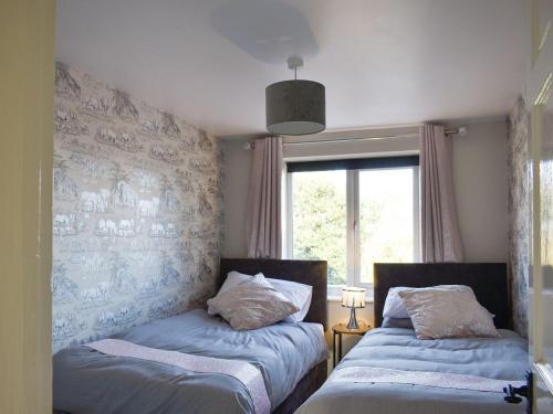 2 camas en una habitación con ventana en Cernunnos Cottage en Leven