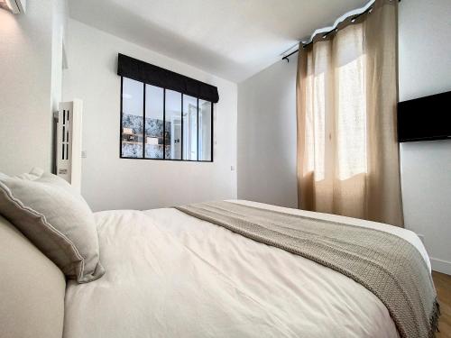 a white bedroom with a bed and a window at AppartChic - appartement standing - plein Centre & Parking privé in Créon