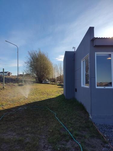 a building with a hose next to a field at Azules 2721 in El Calafate