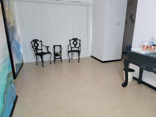 グレンデールにあるOrangewood & 51Ave Homestay - Not a Hotelのピアノ付きの部屋に座る椅子3脚