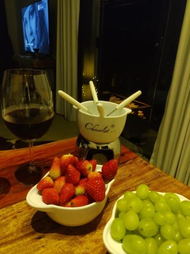 a table with a bowl of strawberries and a glass of wine at Chalé Au Clair de Lune Terê in Teresópolis