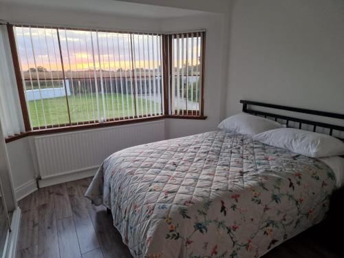 a bedroom with a bed and two large windows at The.deerparkcottage in Lurgan