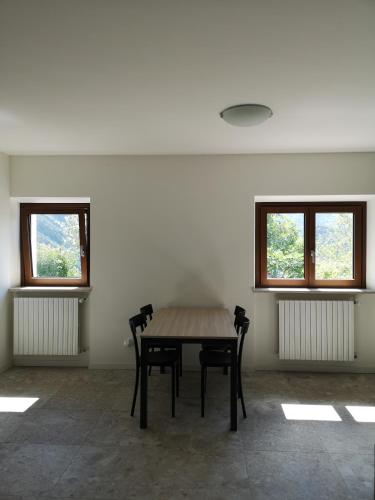 a table and chairs in a room with two windows at Villa tra montagna e laghi 14 posti in Crone