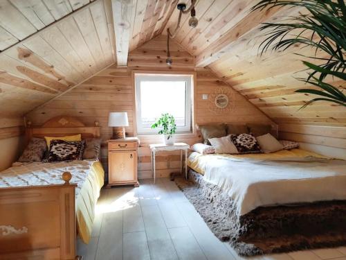 a bedroom with two beds in a wooden house at Ojcowski Zakątek-uroczy domek do wynajęcia in Wola Kalinowska