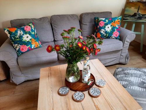 een woonkamer met een tafel met een vaas met bloemen bij Ojcowski Zakątek-uroczy domek do wynajęcia in Wola Kalinowska