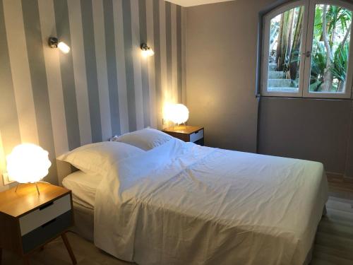 una camera con un letto bianco e due comodini con lampade di Charmant appartement en rez de villa à Vence a Vence