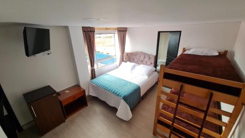 a small bedroom with a bed and a television at Tauko Tú Casa in Paipa