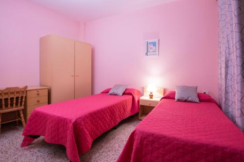 two beds in a room with pink walls at Piso cerca del mar en Alcalá in Alcalá