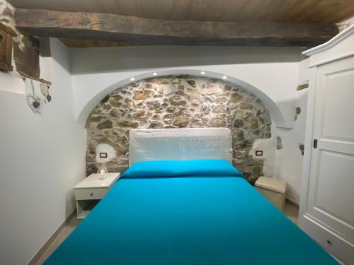 ein Schlafzimmer mit einem blauen Bett und einer Steinmauer in der Unterkunft La mia casetta country chic in Ozieri