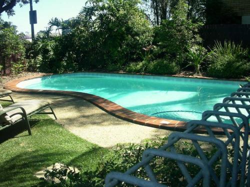 a swimming pool with a wooden path around it at Airport Heritage Motel in Brisbane