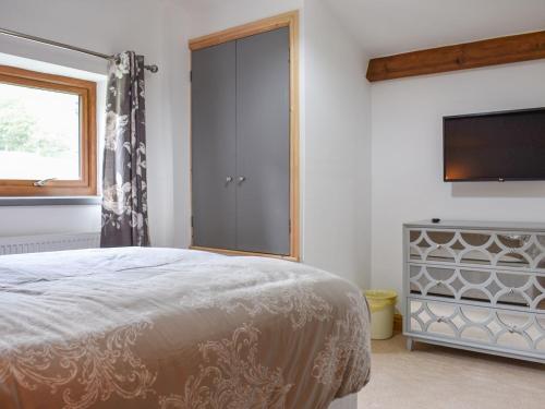 a bedroom with a bed and a flat screen tv at Scaley Beck - Uk39151 in Threlkeld