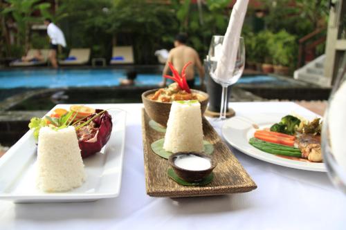 a table with two plates of food and a glass of wine at Mekong Angkor Deluxe Hotel in Siem Reap