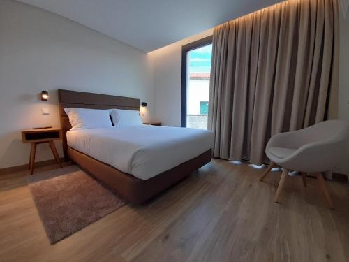 a bedroom with a bed and a chair and a window at Casas da Serra - Soeima Housing in Alfândega da Fé