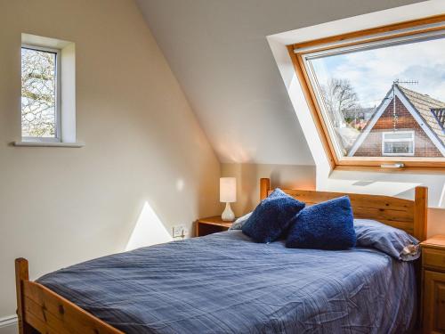 Un dormitorio con una cama con almohadas azules y una ventana en Oakfield en Shrewton